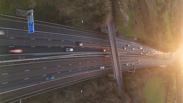 Aerial view of a sprawling motorway cutting through the landscape, with blurred cars speeding on the asphalt, Birmingham, England, United Kingdom.