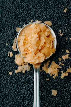 Spoon filled with nutritional yeast flakes on textured dark background