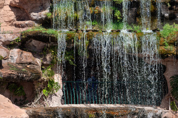 Water flows down a rocky surface surrounded by lush greenery in Morocco's scenic landscape.
