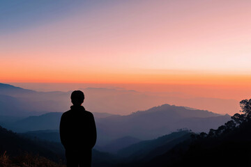 Person Silhouetted Against a Beautiful Sunrise Over Mountain Landscape