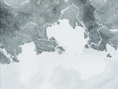 Aerial view of a frozen expanse, where the icy grip of winter paints a stark, monochrome canvas across Lake Galve, Trakai, Lithuania.