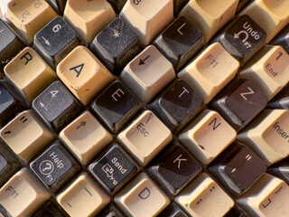 Vintage computer keyboard with aged beige surface and weathered buttons. Retro desktop technology