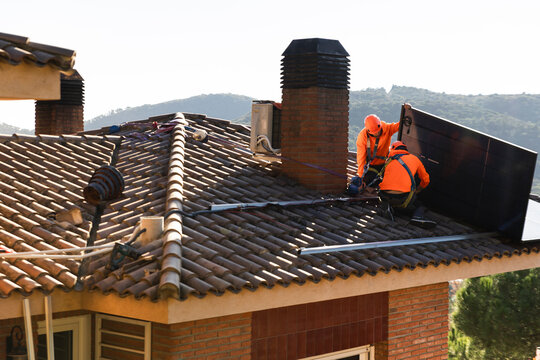 Technicians installing solar panel on roof in Barcelona with teamwork