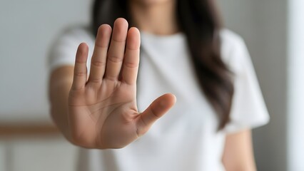 Obraz premium Woman Holding Up Hand in Stop Gesture, Symbolizing Refusal, Personal Boundaries, Consent, or Saying No