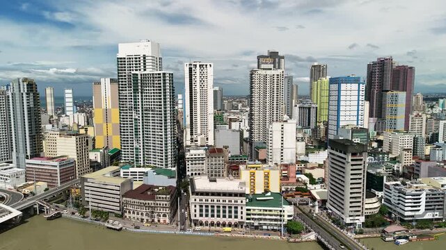 Aerial view over Binondo Chinatown and the Pasig River in Manila with high rise condominiums heritage waterfront buildings and cloudy sky
