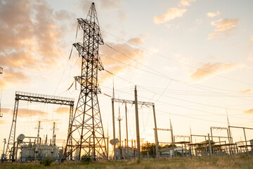 Sunset over power lines and transmission towers in a utility area with equipment and structures