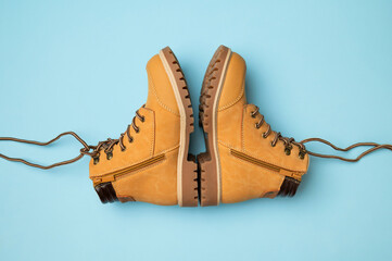 Stylish youth children's yellow men's boots made of genuine leather with laces on blue background top view. Rough-soled boots, work shoes, travel footwear. Stylish nubuck shoes
