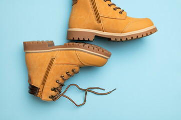 Stylish youth children's yellow men's boots made of genuine leather with laces on blue background top view. Rough-soled boots, work shoes, travel footwear. Stylish nubuck shoes