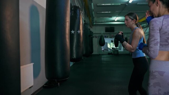 Female boxer practicing punches on a punching bag. two female boxers learn to punch a punching bag.