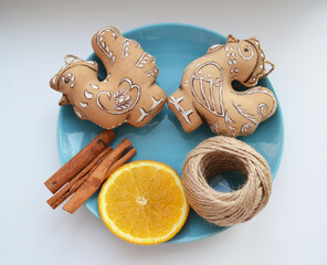 Decorative gingerbread cookies on blue plate with orange and cinnamon sticks