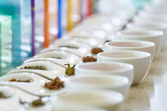 Tea Tasting Setup: Cups, Loose Leaves and Boxes. Focus on cup and tea leaves in center