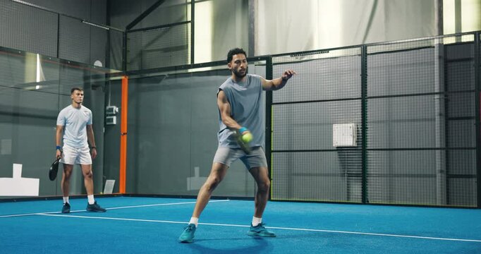 People, playing and padel games on court for fitness, match practice and swing technique. Athlete, men or hitting ball with racket for sports challenge, tennis competition and teamwork for tournament