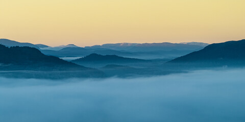 Aerial view of a sea of fog blankets the Caledonian Forest, with layered mountain silhouettes piercing through the ethereal mist, Caledonian Forest, Cairngorms National Park, Scotland.