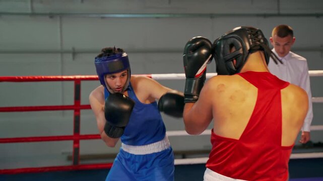 Two opponents are fighting a boxing fight in the ring.. a fight between two young boxers in the ring with a referee who explains the rules, controls the fight and announces the winner.