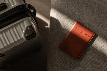 Leather passport on sofa with modern suitcase in natural light