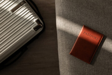 Leather passport on sofa with modern suitcase in natural light