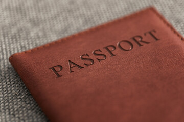Close-up of passport in leather cover on textured fabric