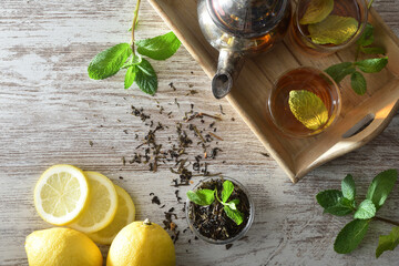 Lemon and mint tea prepared on a wooden tray