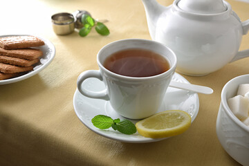 Tea and white ceramic containers on a table with tablecloth