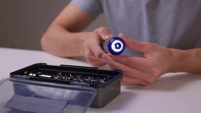 Instructional scene of assembling electric screwdriver bits carefully, Closeup of repair activity involving selecting and installing screwdriver bits on clean table