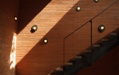 Warm sunlight streams across textured wooden walls and modern stairs