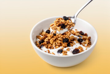 Delicious granola with yogurt and raisins served in a white bowl, perfect for breakfast or healthy snacking. This image showcases a nutritious and appealing meal option.