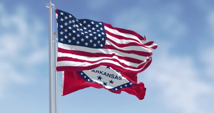 Arkansas state flags waving with the American flags on a clear day