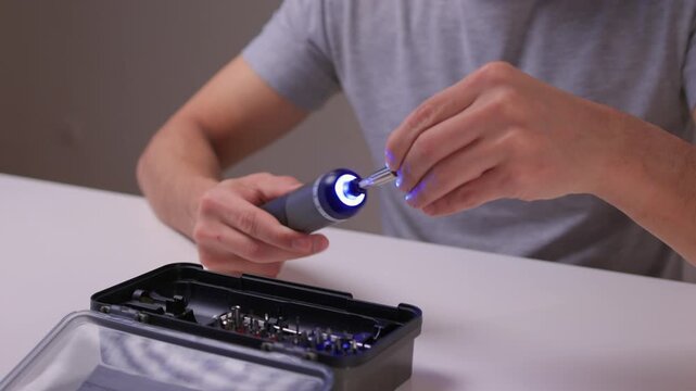 Instructional scene of assembling electric screwdriver bits carefully, Closeup of repair activity involving selecting and installing screwdriver bits on clean table