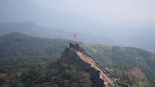 Saffron flag hoisted atop historic Pratapgad Fort, symbolizing Maratha pride, valor and heritage against the majestic Sahyadri backdrop. Built by Shivaji Maharaj, this site echoes centuries of bravery