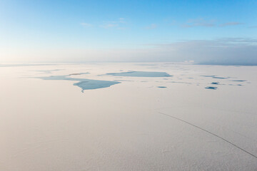 Winter natural landscape: snow and frozen lake view from a drone.