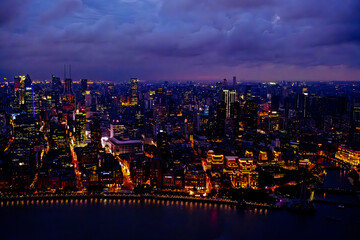 Fototapeta premium aerial view of the Shanghai city skyline at night illuminated by numerous lights and neon signs, specifically around the Bund and Nanjing Road areas