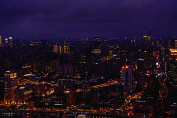Naklejka premium aerial view of the Shanghai city skyline at night illuminated by numerous lights and neon signs, specifically around the Bund and Nanjing Road areas