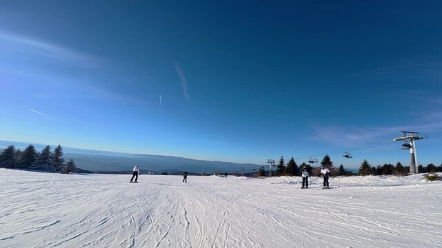 Beautiful POV ski landscape on the mountains. Skier skis down a snowy mountain trail in sunny weather.