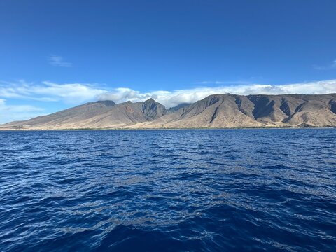 Blue Pacific Ocean with Barren Red Mountain Coastline in Hawaii
