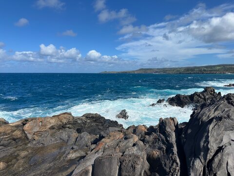 Blue Waves Breaking on Brown Lava Rocks Under Cloudy Sky Hawaii