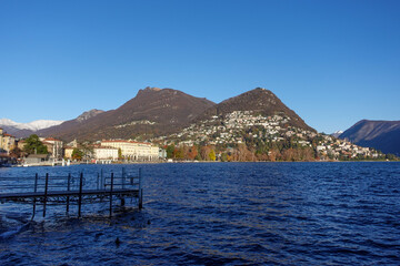 Golden hour over Lake Lugano, where autumn’s warm hues melt into the water and the day exhales in...