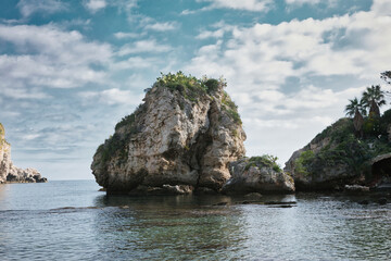 Obraz premium Taormina, Italy - December 09, 2025: Isola Bella beach and island viewed from Taormina, Sicily. The most popular beach in Taormina . Rocky beach with a beautiful sea.