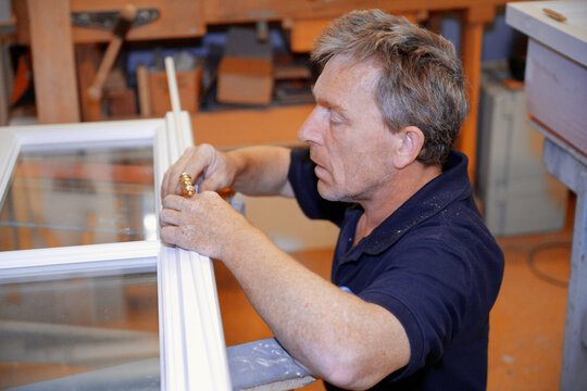Carpenter repairing window frame in workshop in Schaeftlarn Germany