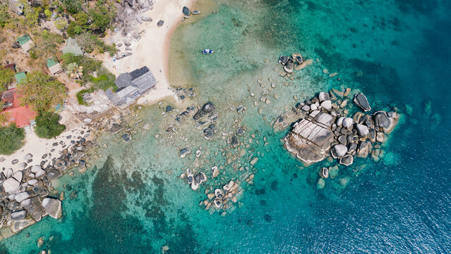 Aerial view of the vibrant turquoise sea contrasting with the rugged rocks and sandy beach, a tropical paradise unfolds, Ko Tao, Surat Thani, Thailand.