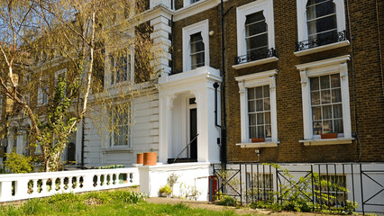 Typical Victorian terraced houses in England. Exterior view of cozy residential buildings in London with metal fence, several floors, windows and front door with molding. Real estate, Living apartment