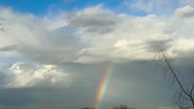 Rainbow over landscape. Rainbow over landscape under cloudy sky.