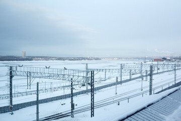 Railway station near the frozen river on the background of the city. Winter landscape.
