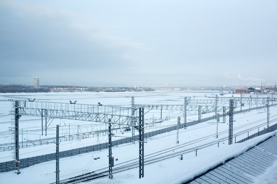 Railway station near the frozen river on the background of the city. Winter landscape.