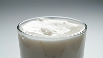 Pouring milk into glass and creating foam with a steady swirl in a kitchen setting in the morning - Powered by Adobe