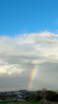 Rainbow over landscape. Rainbow over landscape under cloudy sky.