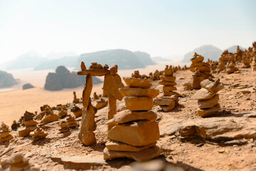 Numerous balanced stone cairns dot the arid landscape of the Wadi Rum desert in Jordan with rocky mountains in the background. 