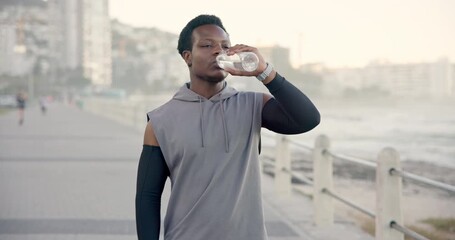 Black man, fitness or drinking with water on promenade for workout break, hydration or recovery. Active, male person or runner with mineral liquid, bottle or aqua beverage for sustainability at beach