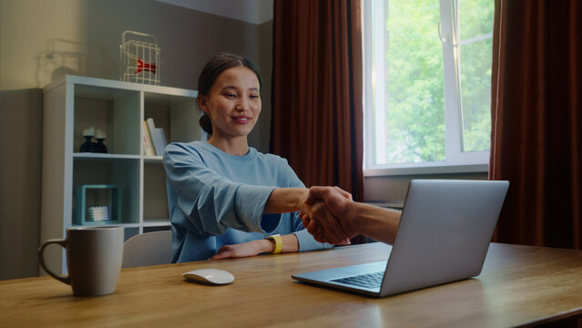 Asian woman shake hand remotely, handshake through laptop screen. Conclusion agreement at home. Female employee virtual meeting. Successful distant job interview. Girl deal video call. Work conference