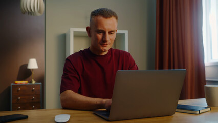 Man remote worker get ready work home. Guy come early morning sit down desk open laptop type keyboard. Male employee surfing net. Busy serious person use pc. Online computer freelancer. Distant job. © Татьяна Епанешникова