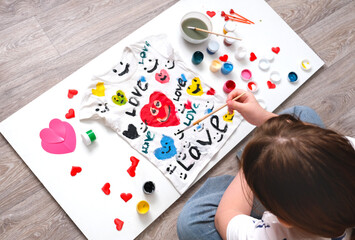 Teenager girl sitting on the floor and painting coloring white t shirt. Creative. Gift for Mothers...
